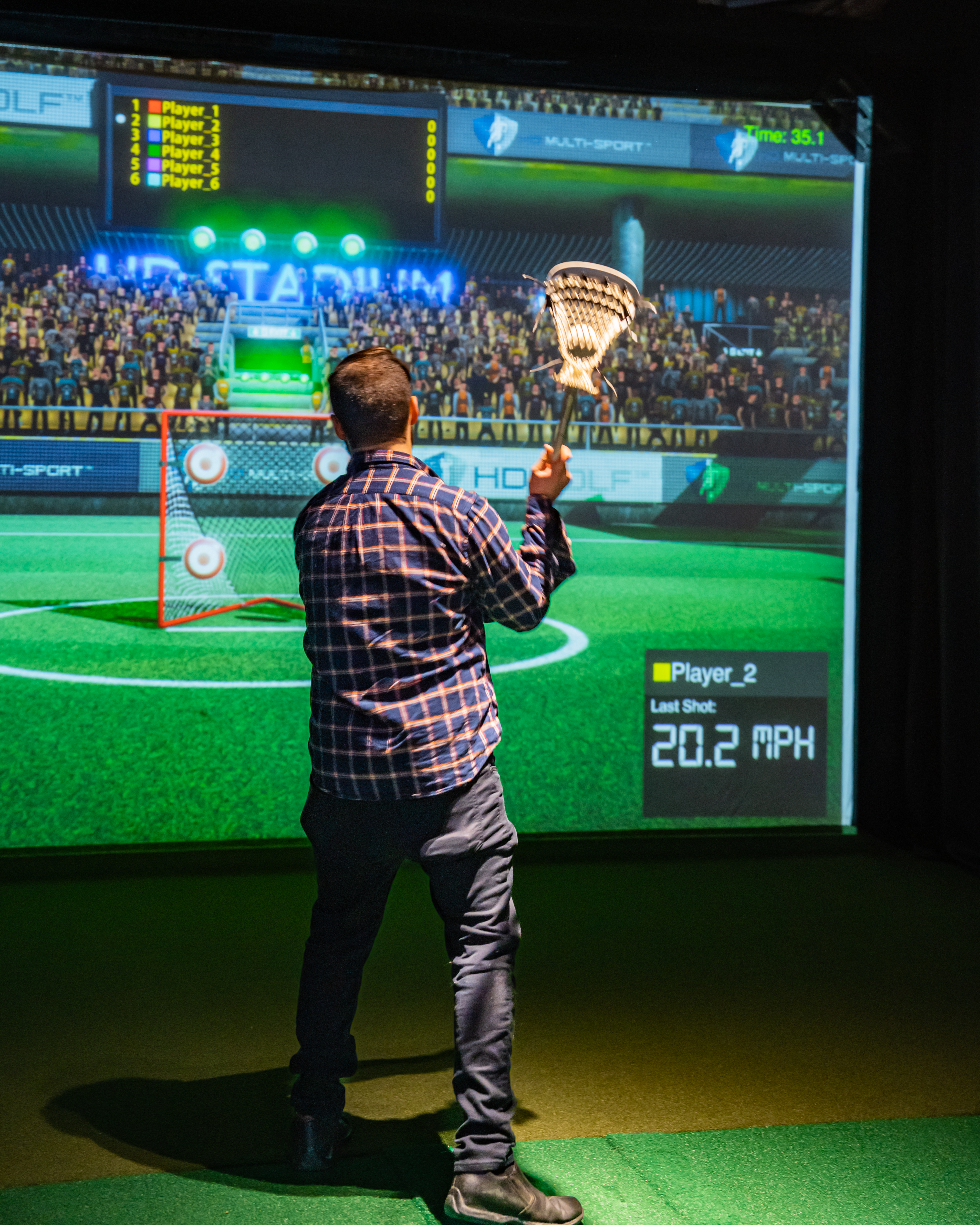 Man playing lacrosse on multi-sport simulator