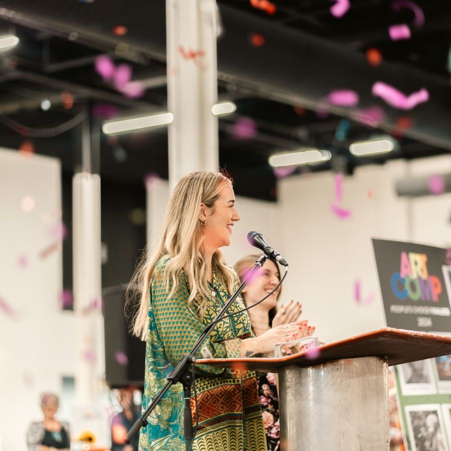 A woman stands at a podium as confetti falls